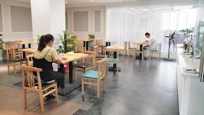 A restaurant with wooden tables and chairs, a waitress, and a customer. - Greentree Inn Yingtan Bus Station Express Hotel (Yingtan)