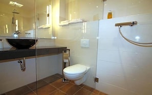 Une salle de bain moderne avec un lavabo entouré de parois en verre, des toilettes et un espace douche.