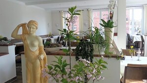 A statue in a dining area with a view of a brick building outside.