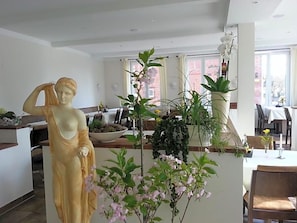 A statue in a dining area with a view of a brick building outside.