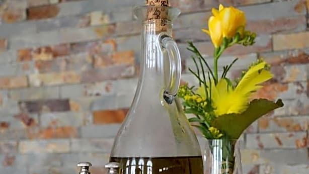 A clear glass bottle with a cork stopper, a metal tray, and two metal salt and pepper shakers.