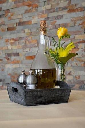A clear glass bottle with a cork stopper, a metal tray, and two metal salt and pepper shakers.
