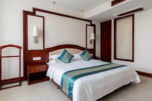 Un cuarto de hotel ordenado con una cama grande, mesitas de noche, un armario y un espejo.
