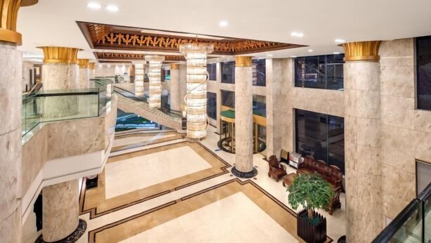 A spacious lobby with marble flooring, a central staircase, and a seating area with a large plant. - Royal Plaza Hotel (Quzhou)
