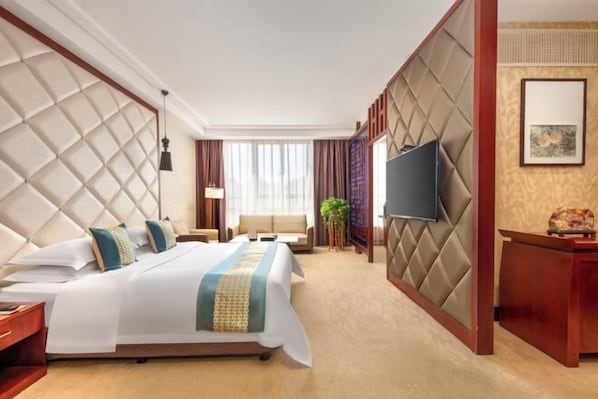 Quarto de hotel com uma cama grande, televisão, escrivaninha e janela.