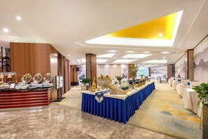A hotel lobby with a reception desk, a buffet area, and a long table with chairs. - Royal Plaza Hotel (Quzhou)