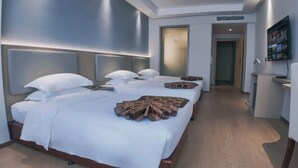 A hotel room with a large bed, bedside tables, a TV, and a hallway leading to another room. - Royal Plaza Hotel (Quzhou)