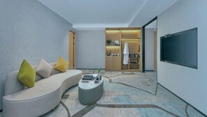 A modern living room with a curved sofa, a coffee table, and a flat-screen TV. - Royal Plaza Hotel (Quzhou)