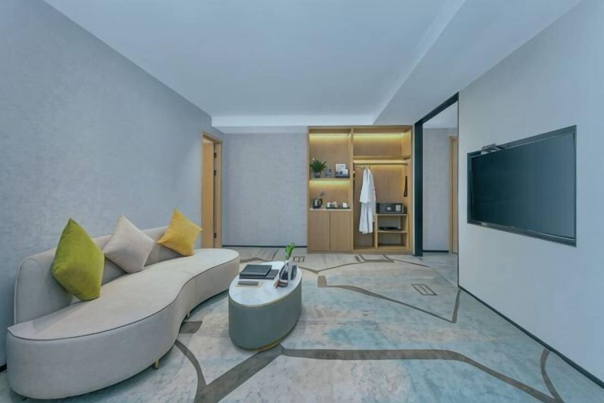 A modern living room with a curved sofa, a coffee table, and a flat-screen TV.