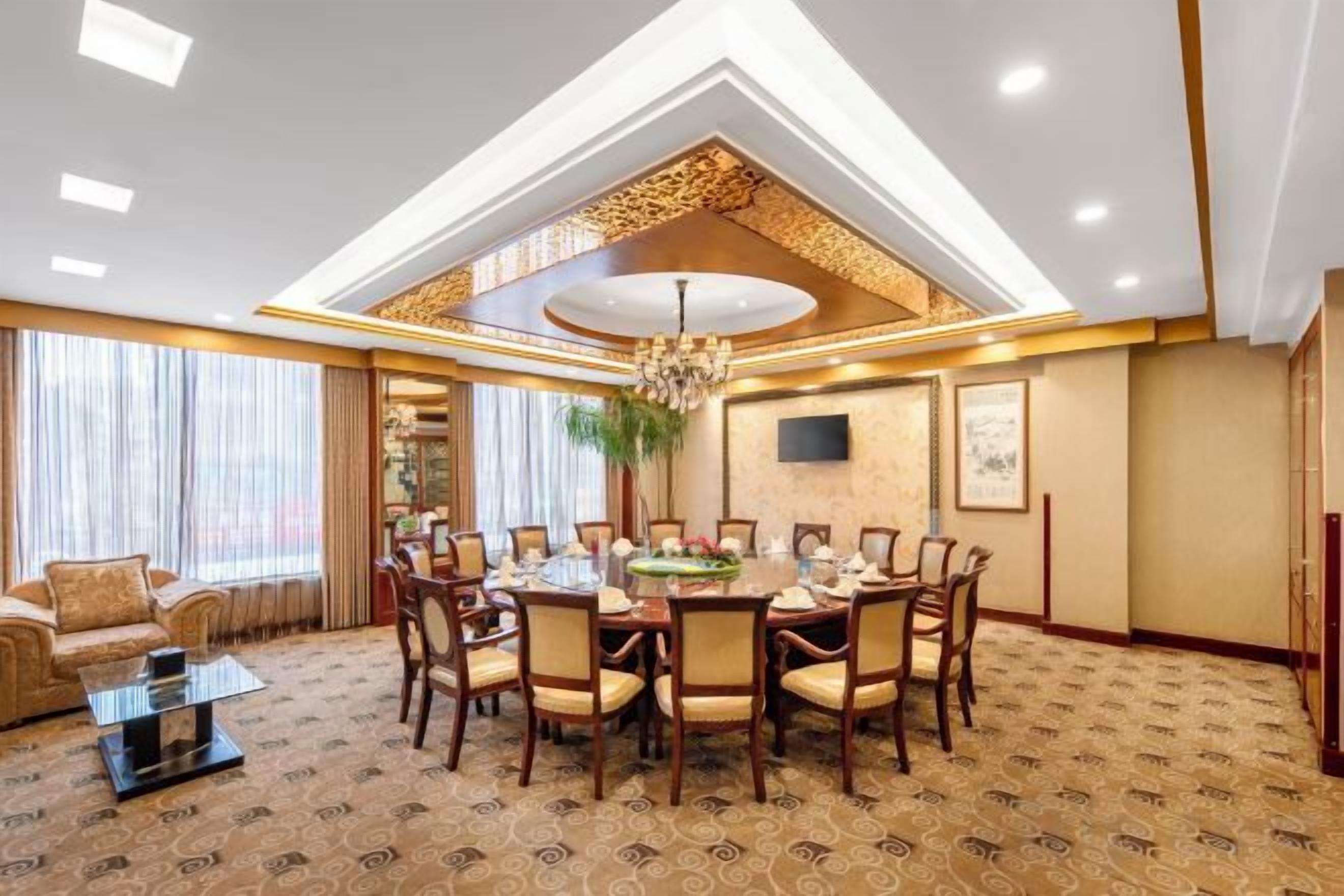 A hotel dining room with a round table, chairs, and a chandelier.