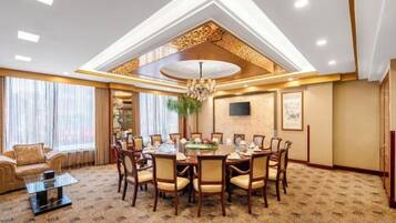 A hotel dining room with a round table, chairs, and a chandelier.