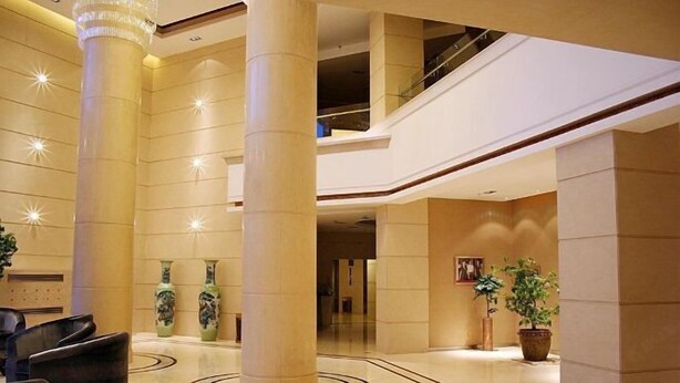 Un hall espacioso con techos altos, grandes columnas y una escalera central.