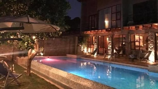 Une maison moderne à deux étages, dotée d’une piscine, d’un espace extérieur aménagé et d’un patio bien éclairé.