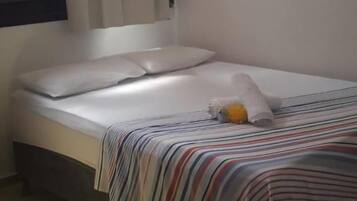A small, single-bed room with a striped bedspread, a pillow, and a blanket.