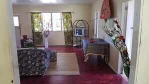 A living room with a sofa, a small table, a TV, and a decorative wall piece. - Navutovuto Accommodation (Kadavu Island)