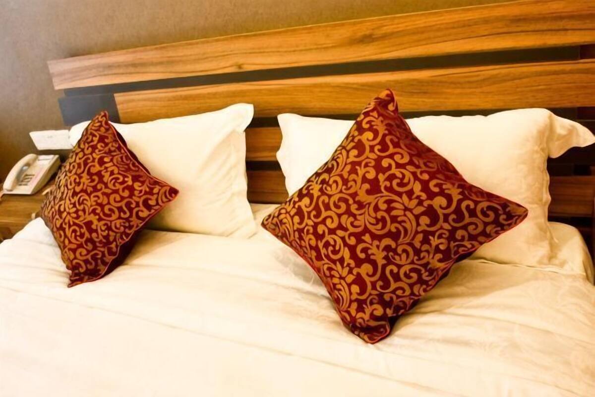 Una cama con dos almohadas estampadas y un cabecero de madera.