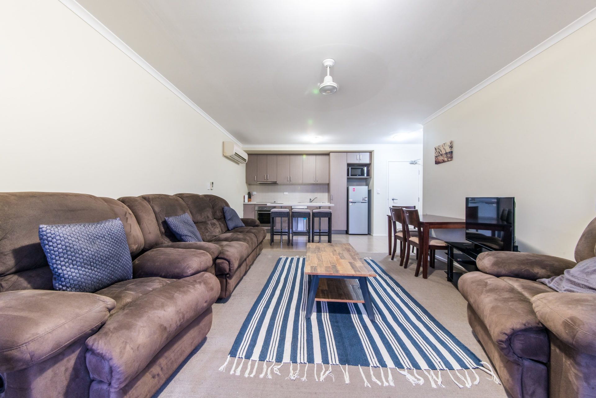 A living room with a sofa set, a coffee table, and a striped rug.