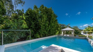 A swimming pool with a tiled deck, surrounded by lush greenery and a clear blue sky. - Candlelight - Airlie Beach (Airlie Beach)
