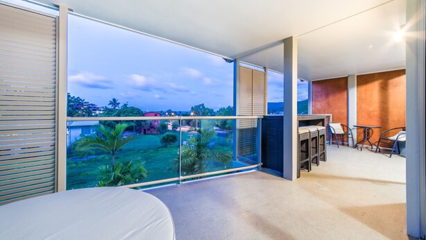 A balcony with a view of a residential area, a bar area with seating, and a bed. - Candlelight - Airlie Beach (Airlie Beach)
