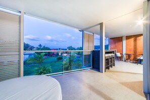 A balcony with a view of a residential area, a bar area with seating, and a bed.
