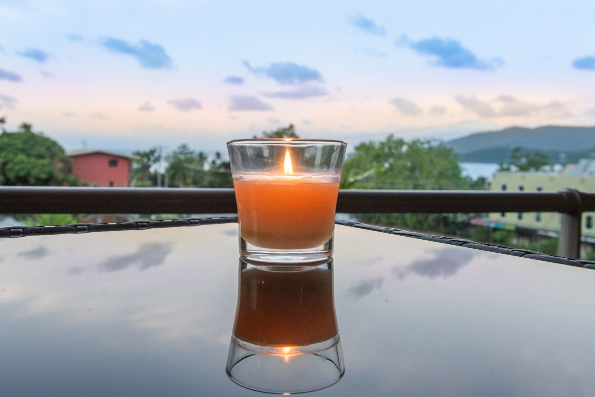 A glass of orange juice on a reflective table with a scenic view of mountains and trees in the background.