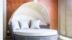 A round, wicker daybed with a canopy, pillows, and a small table. - Candlelight - Airlie Beach (Airlie Beach)
