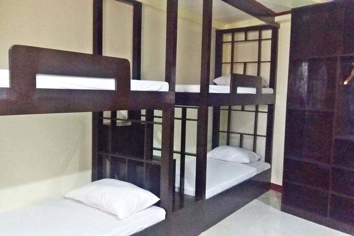 Quarto com beliche, cabeceira de madeira e uma mesinha.
