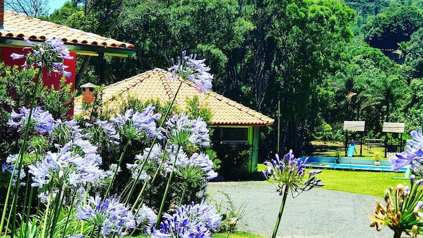 Um edifício com telhado de cerâmica, cercado por vegetação exuberante e área de piscina.