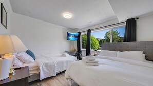 Een hotelkamer met twee bedden, een televisie, een bureau met lamp en een raam met gordijnen.