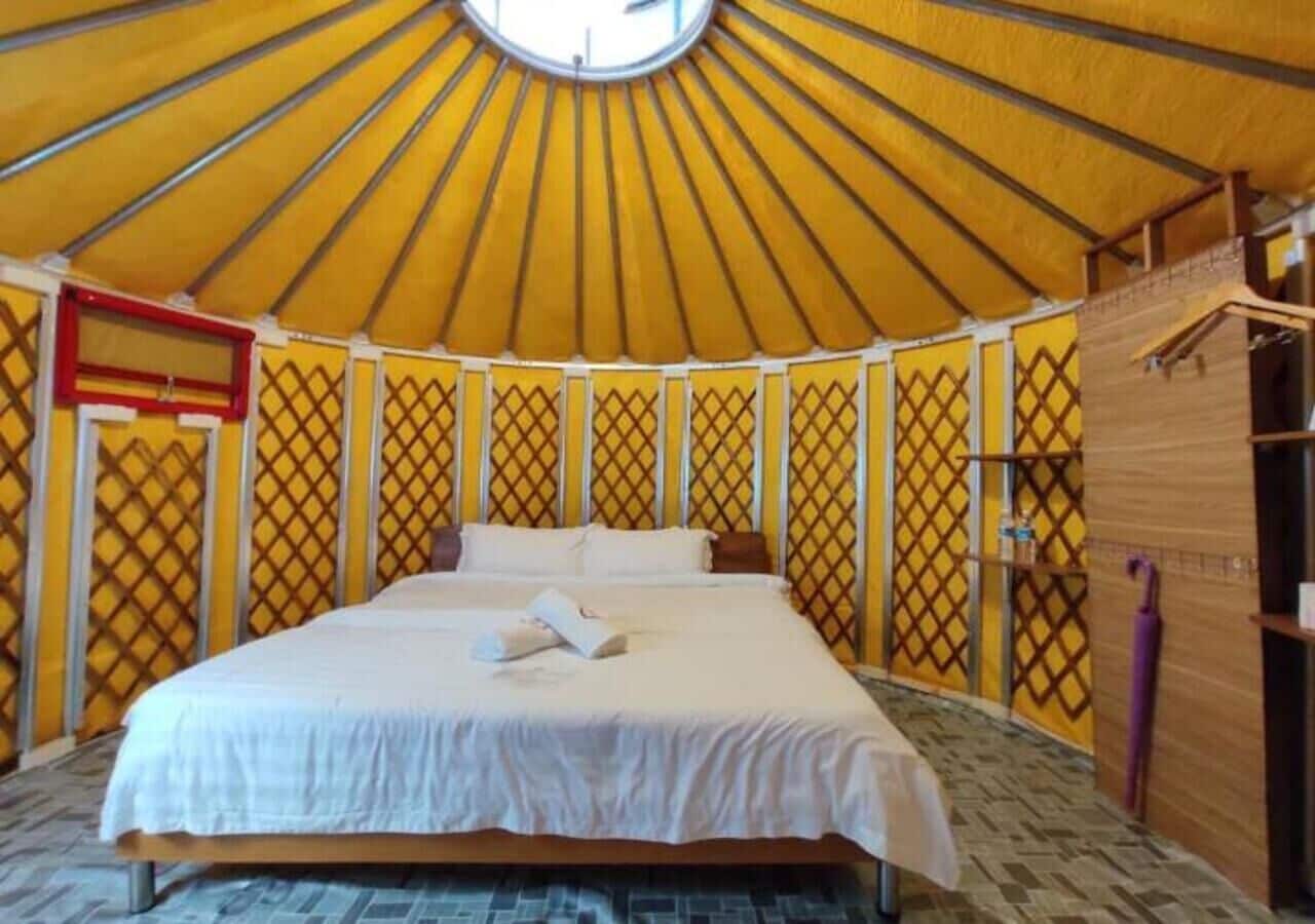 A bed in a yurt with a patterned wall and a wooden shelf.