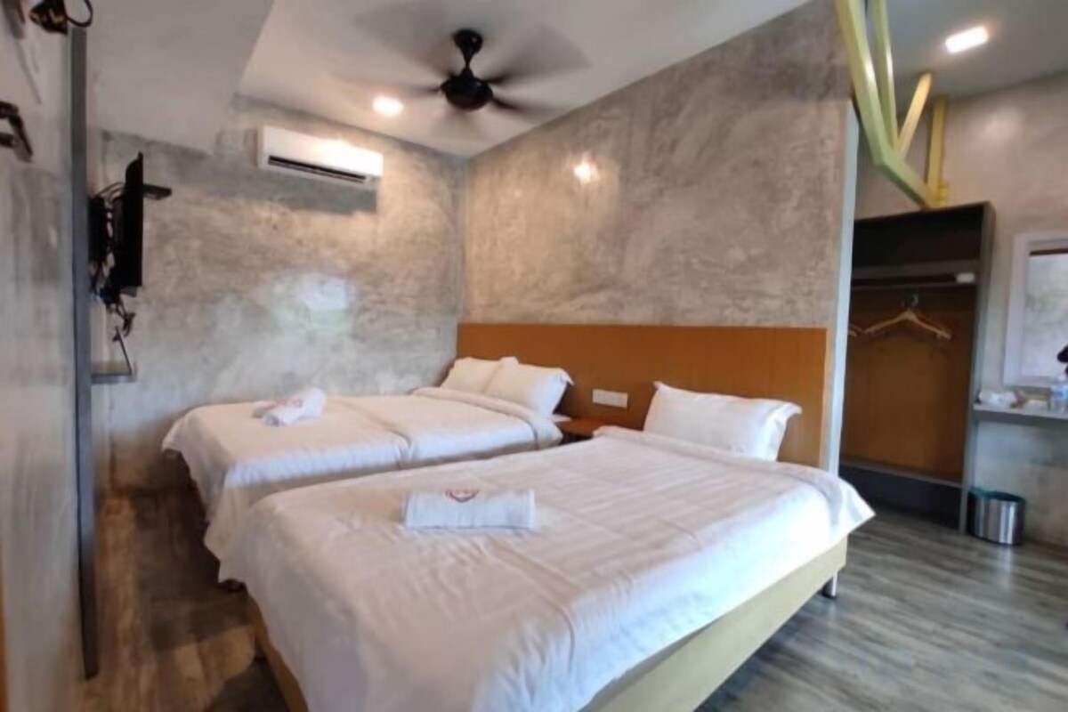 A hotel room with two beds, a ceiling fan, an air conditioning unit, and a wooden headboard.