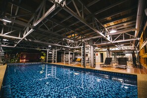 An indoor swimming pool with a tiled floor and a high ceiling with metal beams. - Rick Resort Teluk Intan (Teluk Intan)