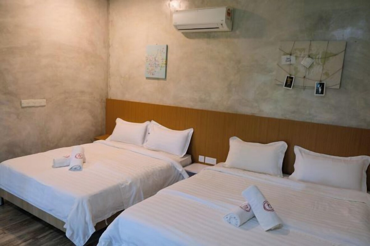 A hotel room with two beds, white linens, and a wooden headboard.