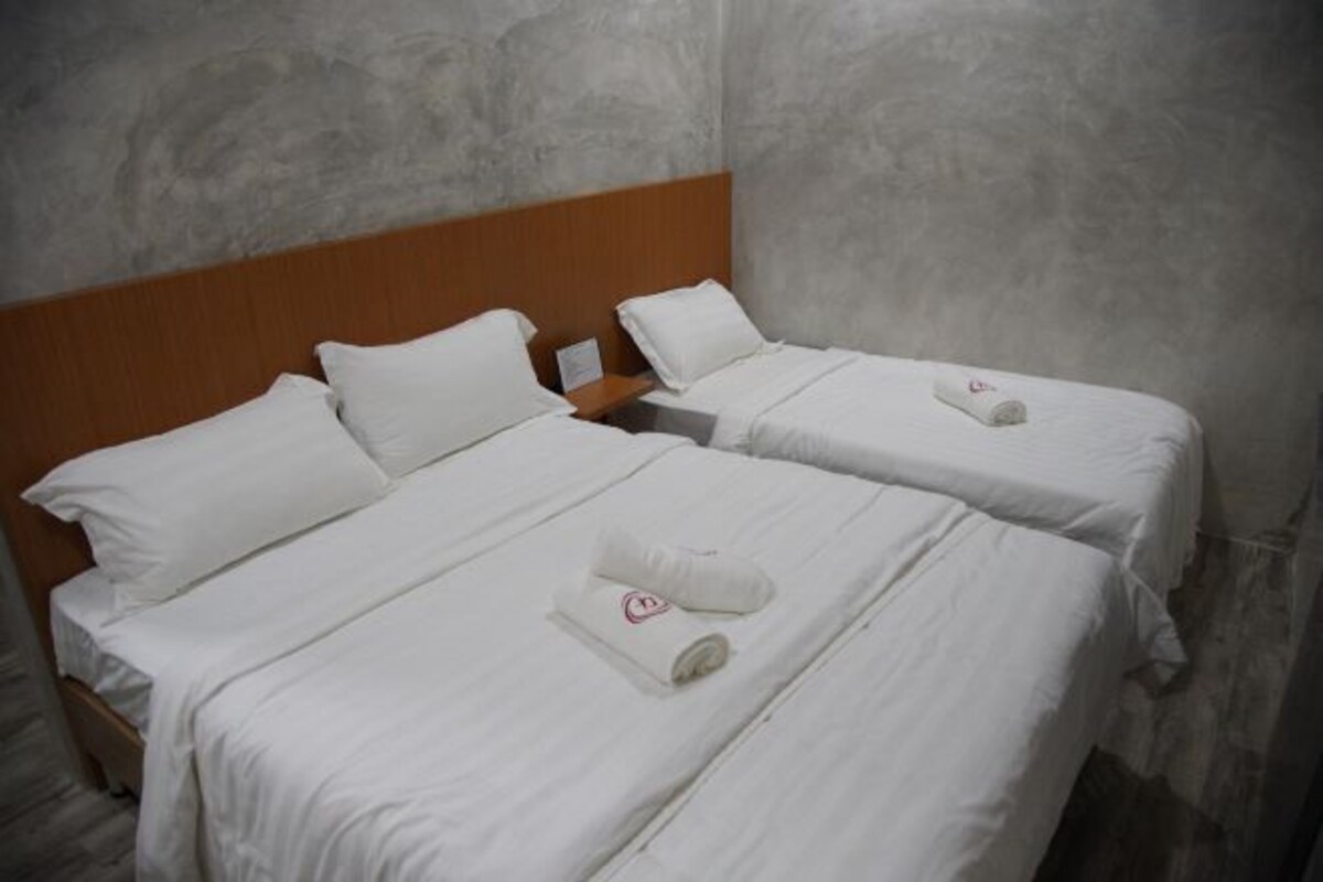 Habitación de hotel con dos camas individuales, cada una con sábanas y almohadas blancas, y cabeceros de madera.