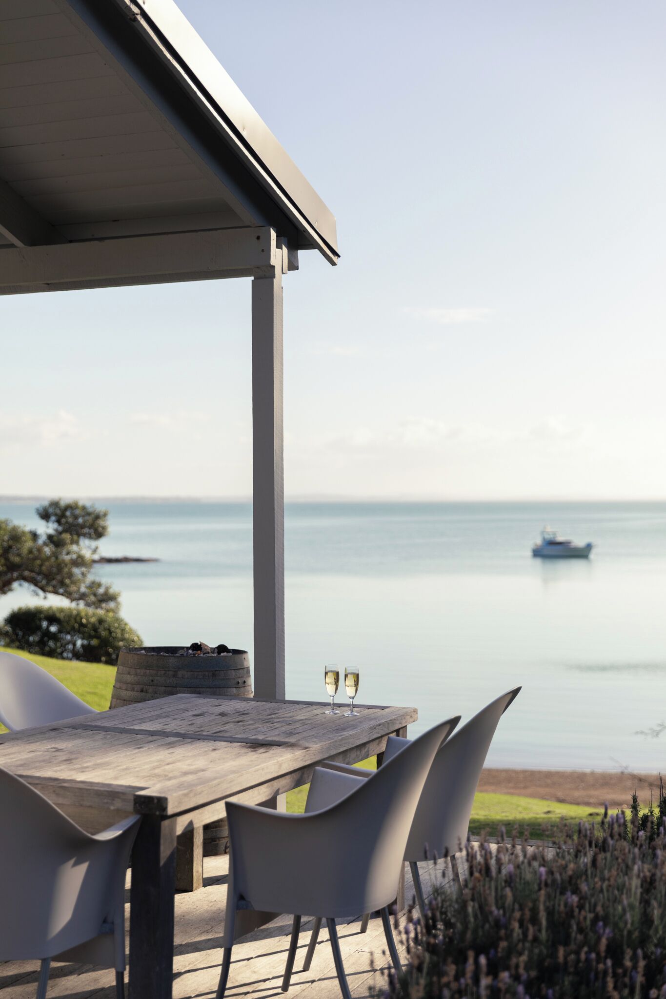 Une table en bois avec des chaises, une vue sur la mer et un bateau au loin.
