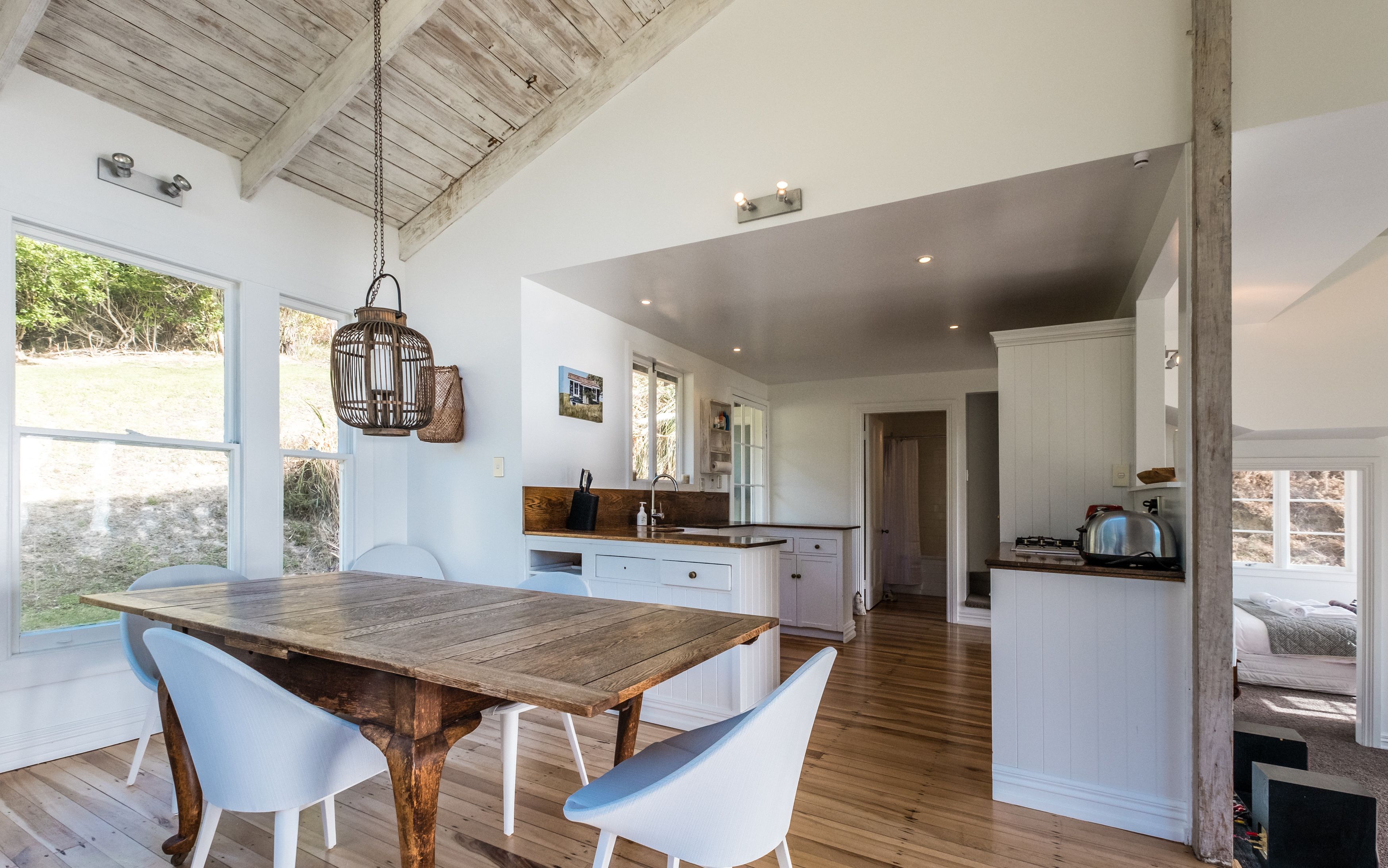 A spacious kitchen with wooden flooring, white cabinetry, and a large wooden table with chairs.