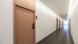 A long, narrow hallway with wooden doors and a light-colored floor. - Moca Hotel (Bangkok)