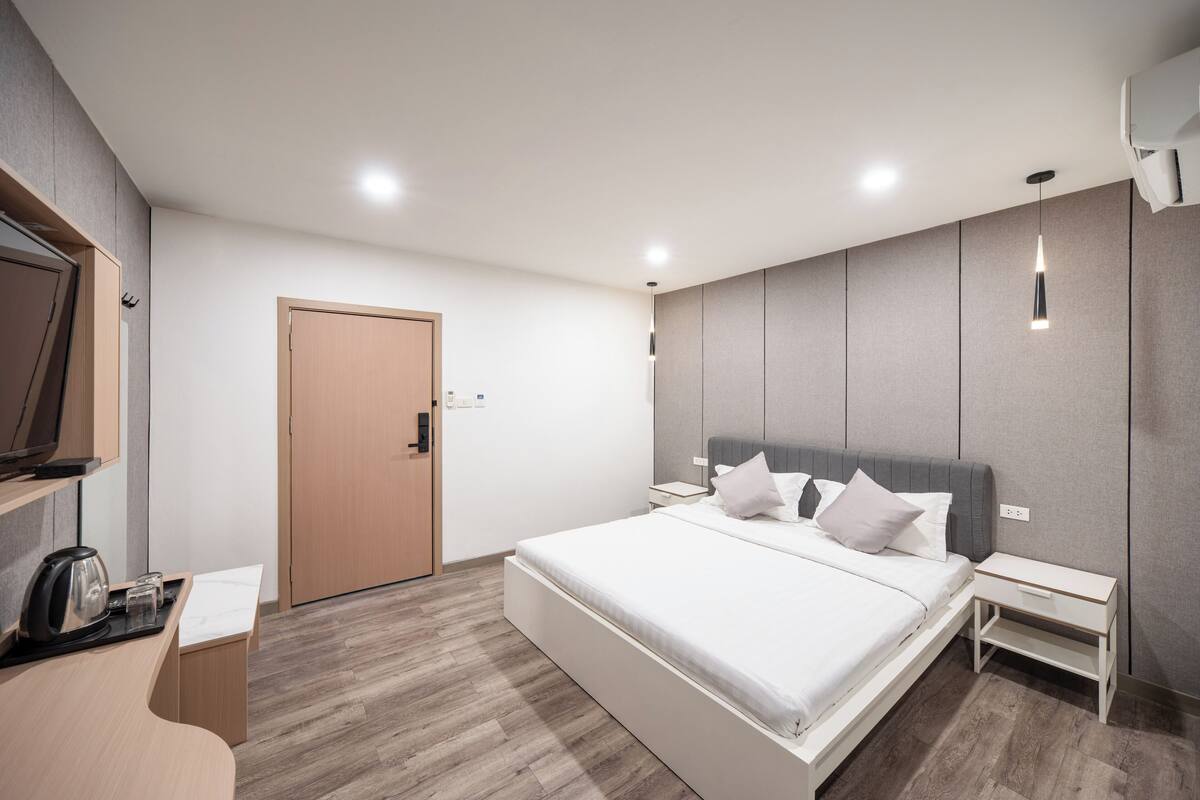 Une chambre d’hôtel moderne dotée d’un grand lit, de tables de chevet, d’un téléviseur à écran plat et d’un bureau en bois.