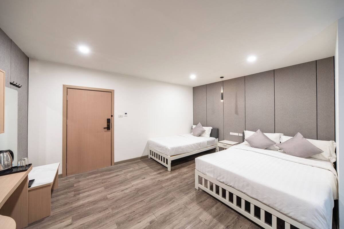 Une chambre d’hôtel moderne avec deux lits simples, un bureau en bois et une armoire intégrée.