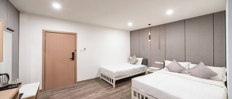 A modern hotel room with two single beds, a wooden desk, and a built-in wardrobe.