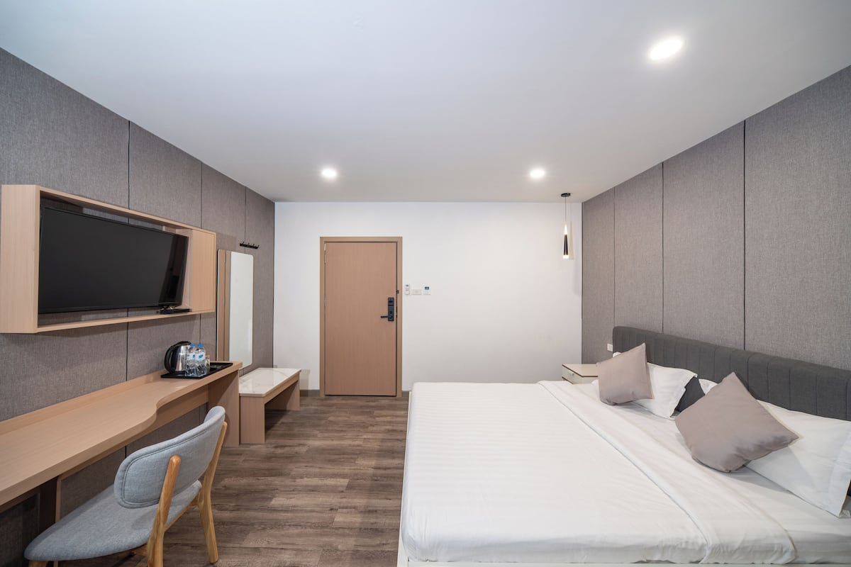 Une chambre d’hôtel moderne équipée d’un lit, d’un bureau avec une chaise, d’une télévision et d’une porte.