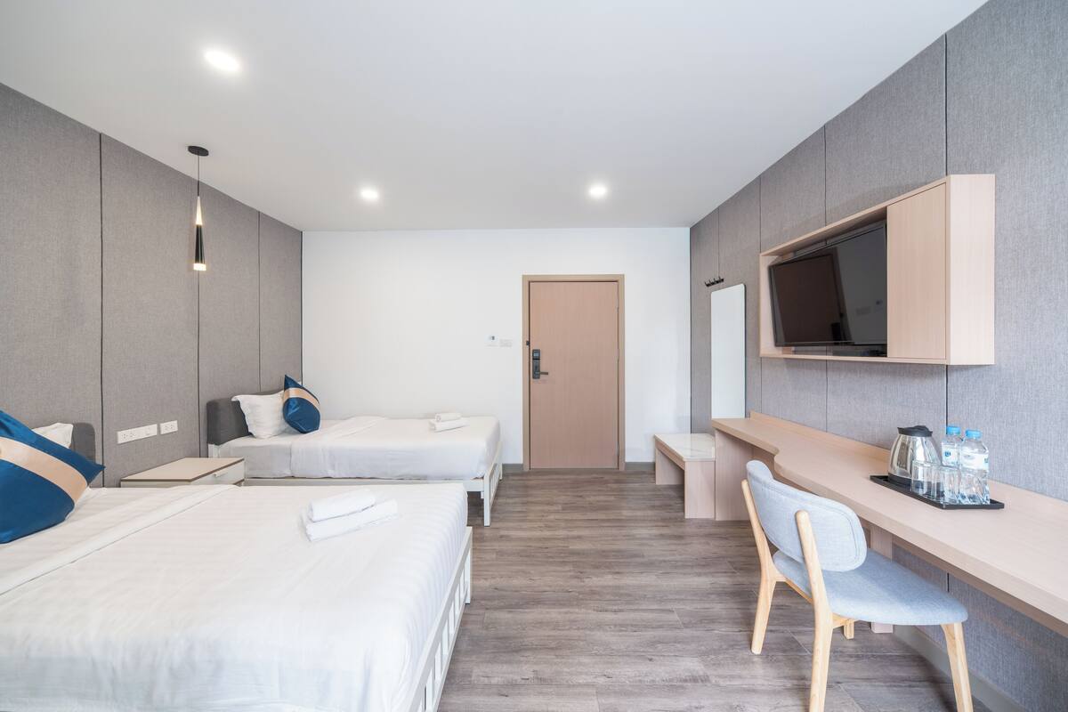 Une chambre d’hôtel moderne équipée de deux lits, d’un bureau, d’une chaise, d’une télévision et d’une porte.