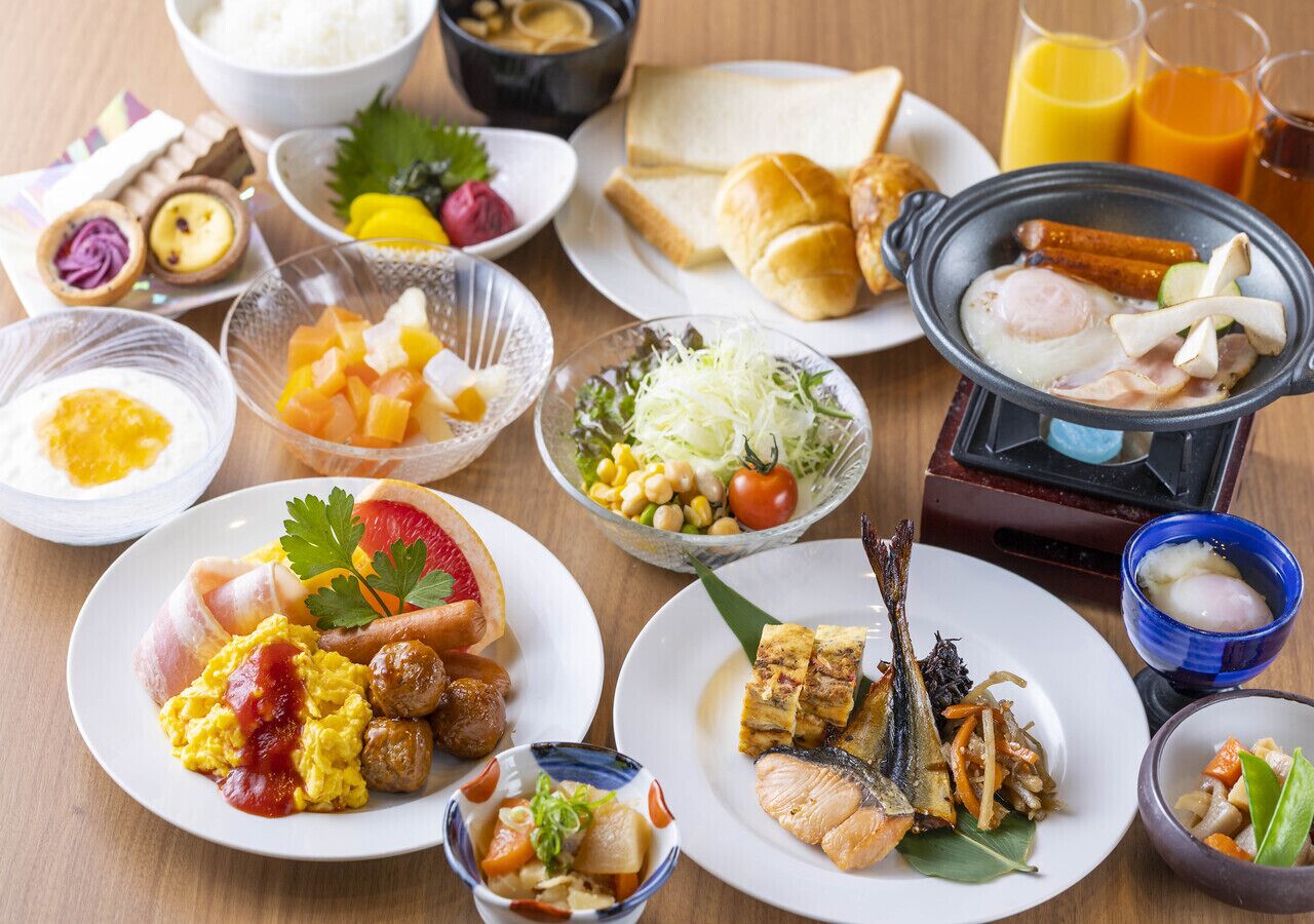 Variedad de platos que incluyen huevos revueltos, salchichas y pescado a la parrilla sobre una mesa de madera.