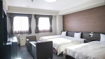 Ein Hotelzimmer mit zwei Betten, einem Schreibtisch, einem Stuhl und einem Fernseher.