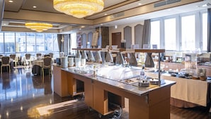 Buffet disposat amb diverses estacions de servei, una làmpada de cristall i vista del menjador.