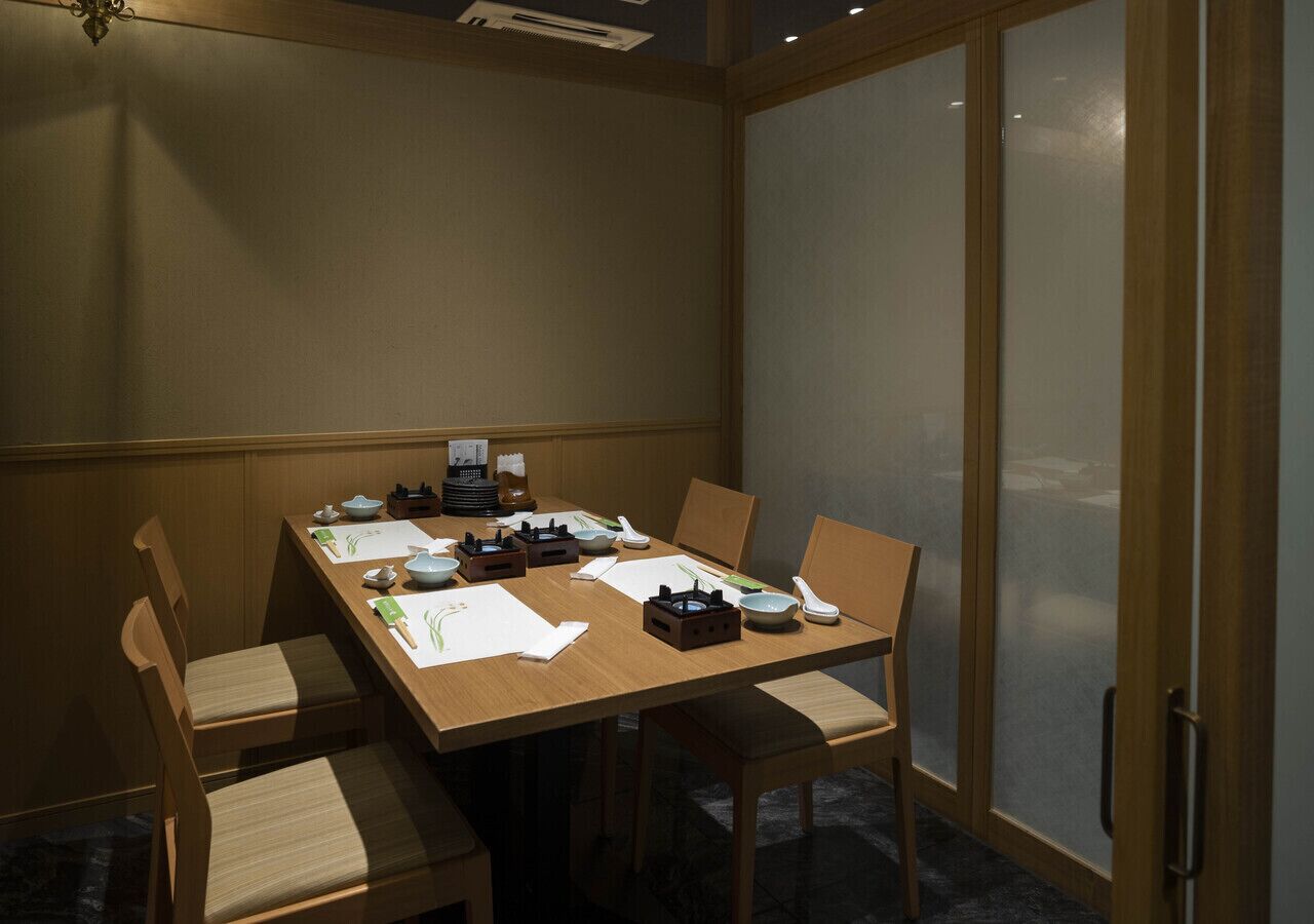Un comedor con una mesa de madera, sillas y un separador de vidrio.