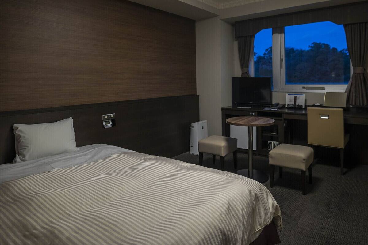 Una habitación de hotel con cama, escritorio, silla y televisor.