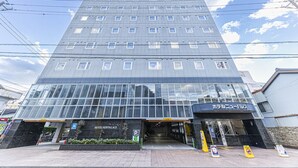 Un hotel de diverses plantes amb façana de vidre moderna, entrada visible i un senyal que indica que és un hotel.