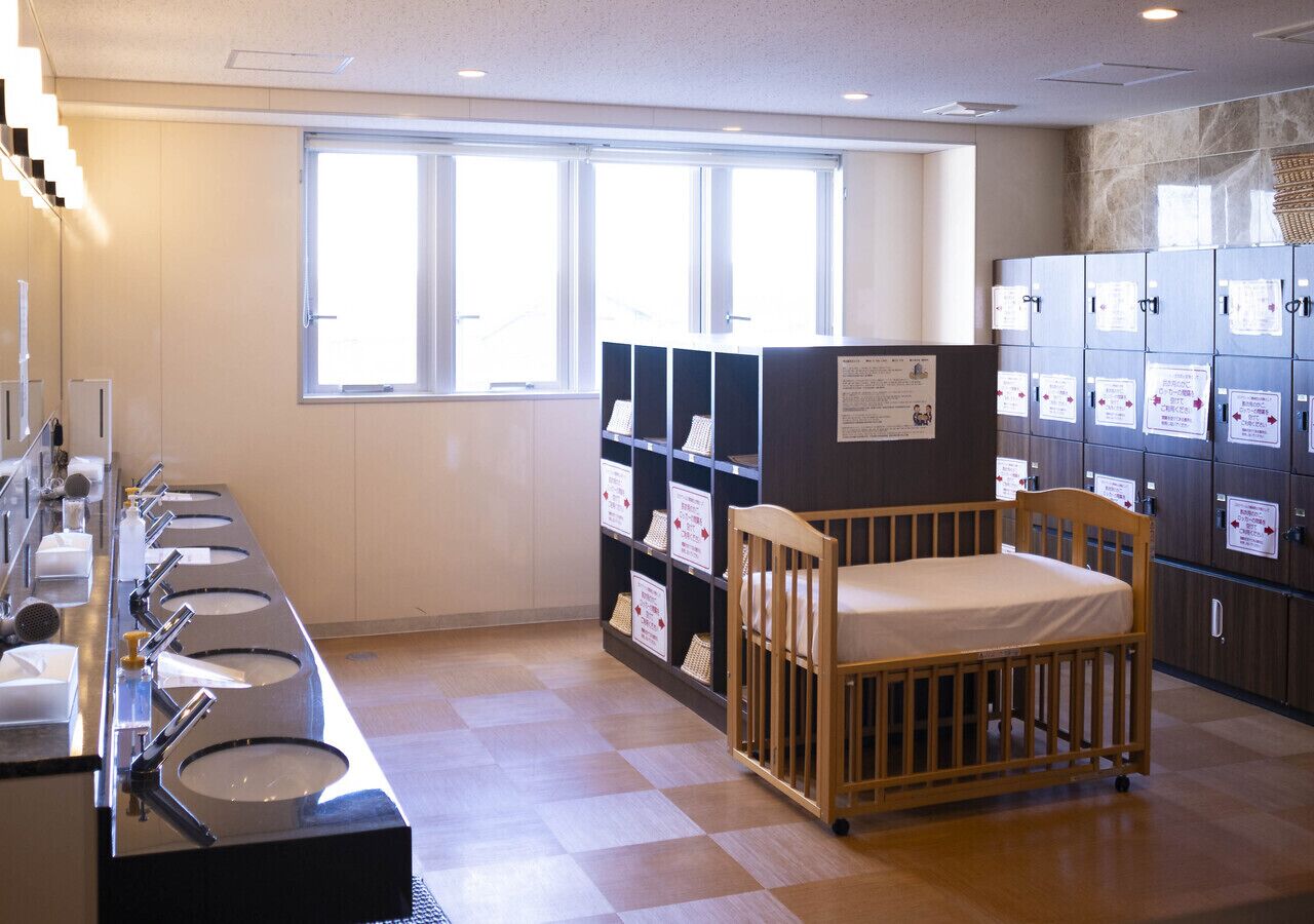 A baby changing room with sinks, a crib, and storage cabinets.