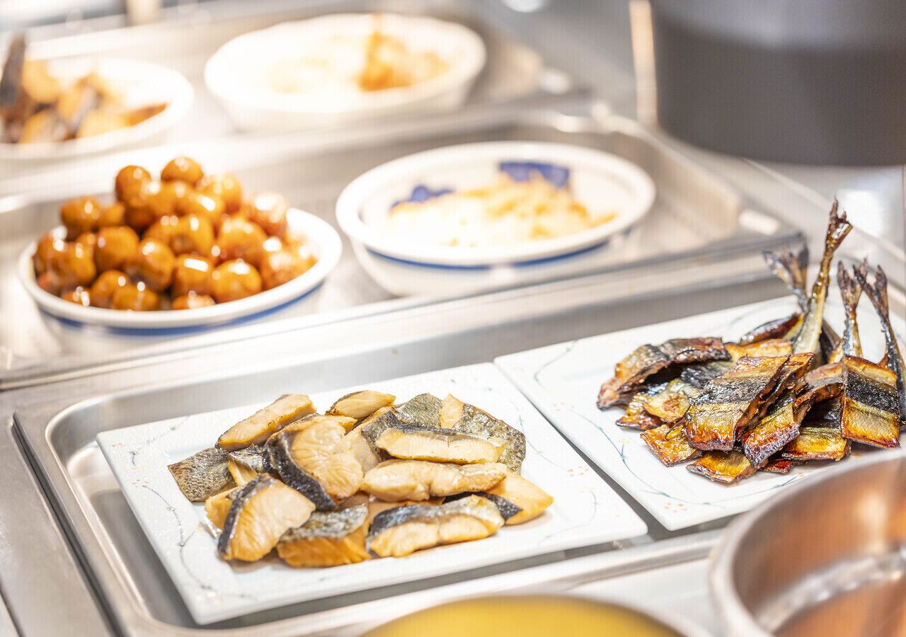 En buffet med forskellige retter, herunder stegt fisk og andre tilberedte spiser.